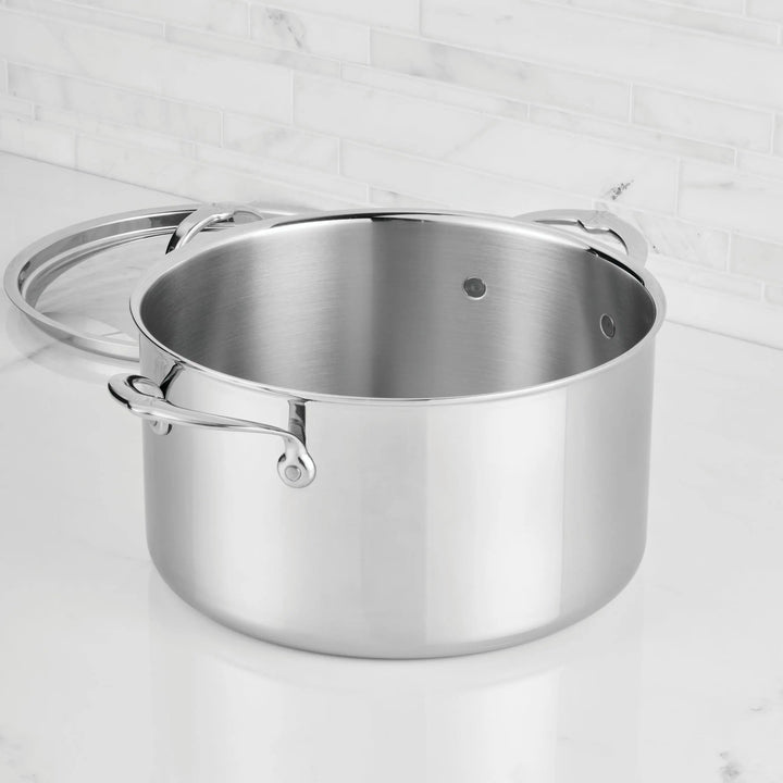 Stainless steel pot with lid on a light gray background